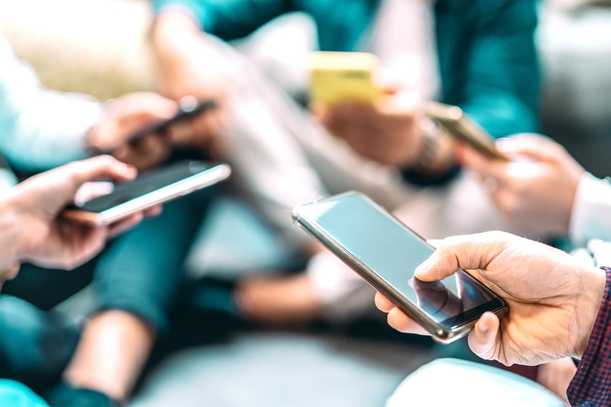 Several hands holding smartphones.