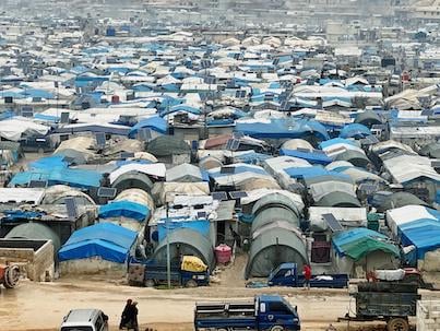 Tents with blue, white and gray coverings in a refugee camp in Syria.