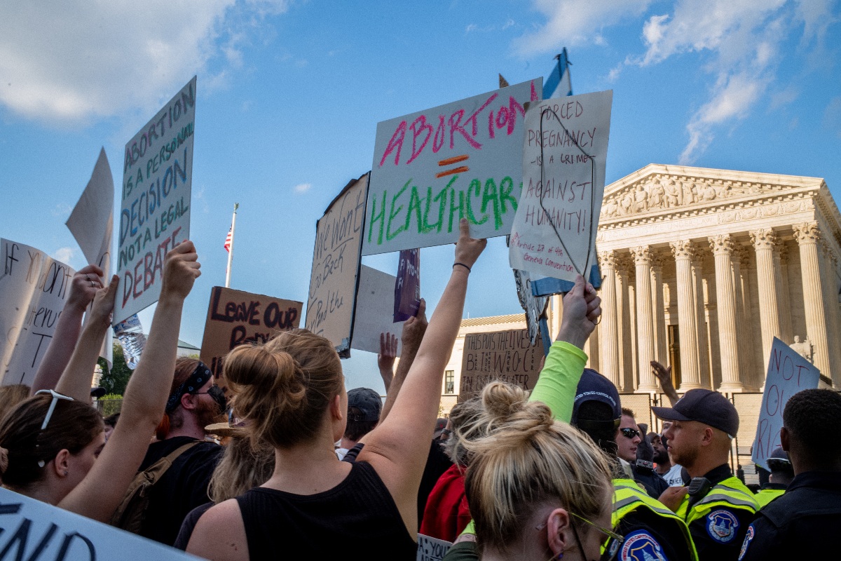 Protesters at the Supreme Court hold up signs; one reads "Abortion equals health care."
