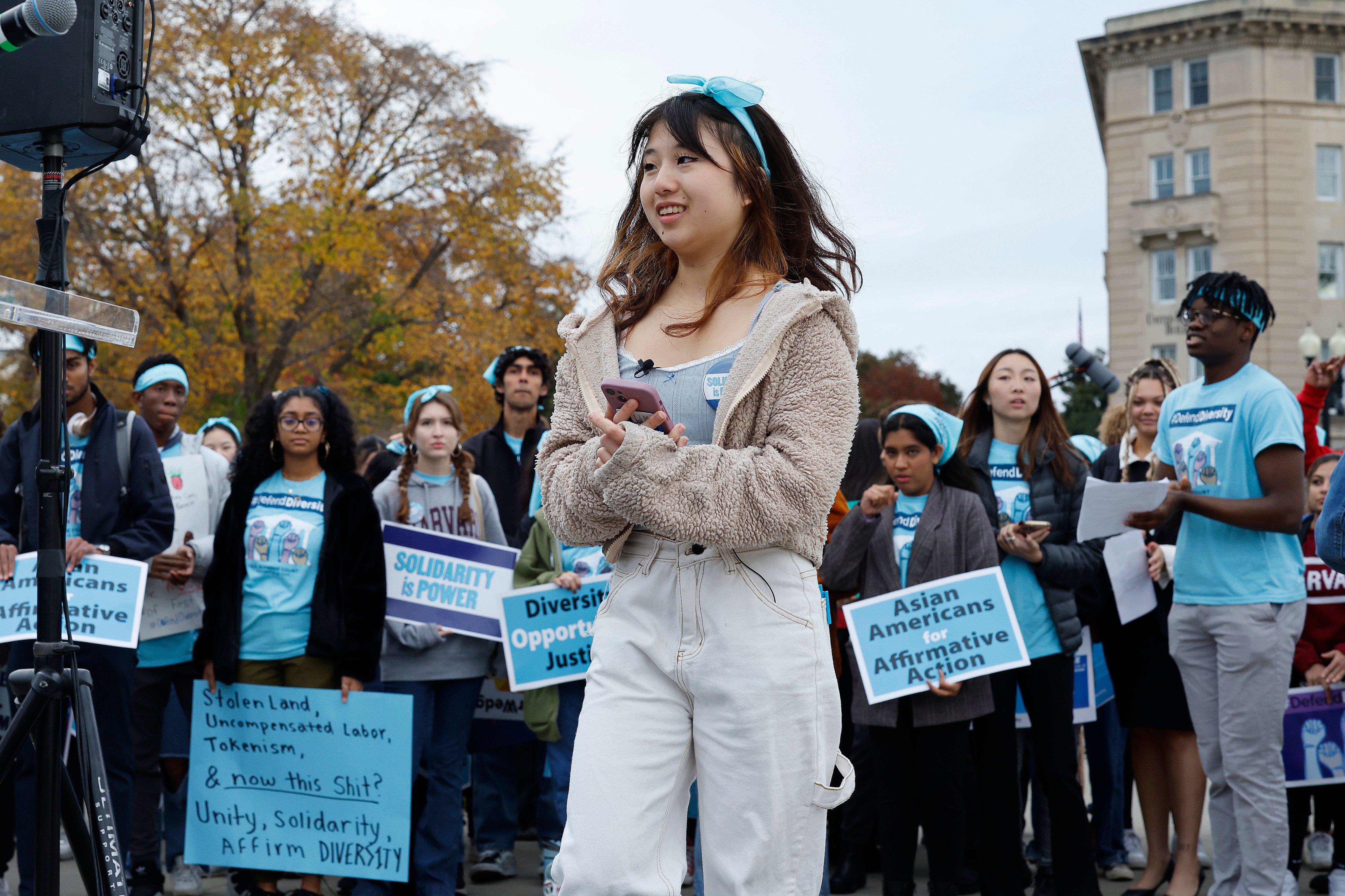 A group of advocates hold signs that say "Asian Americans for Affirmative Action" and "Solidarity Is Power."