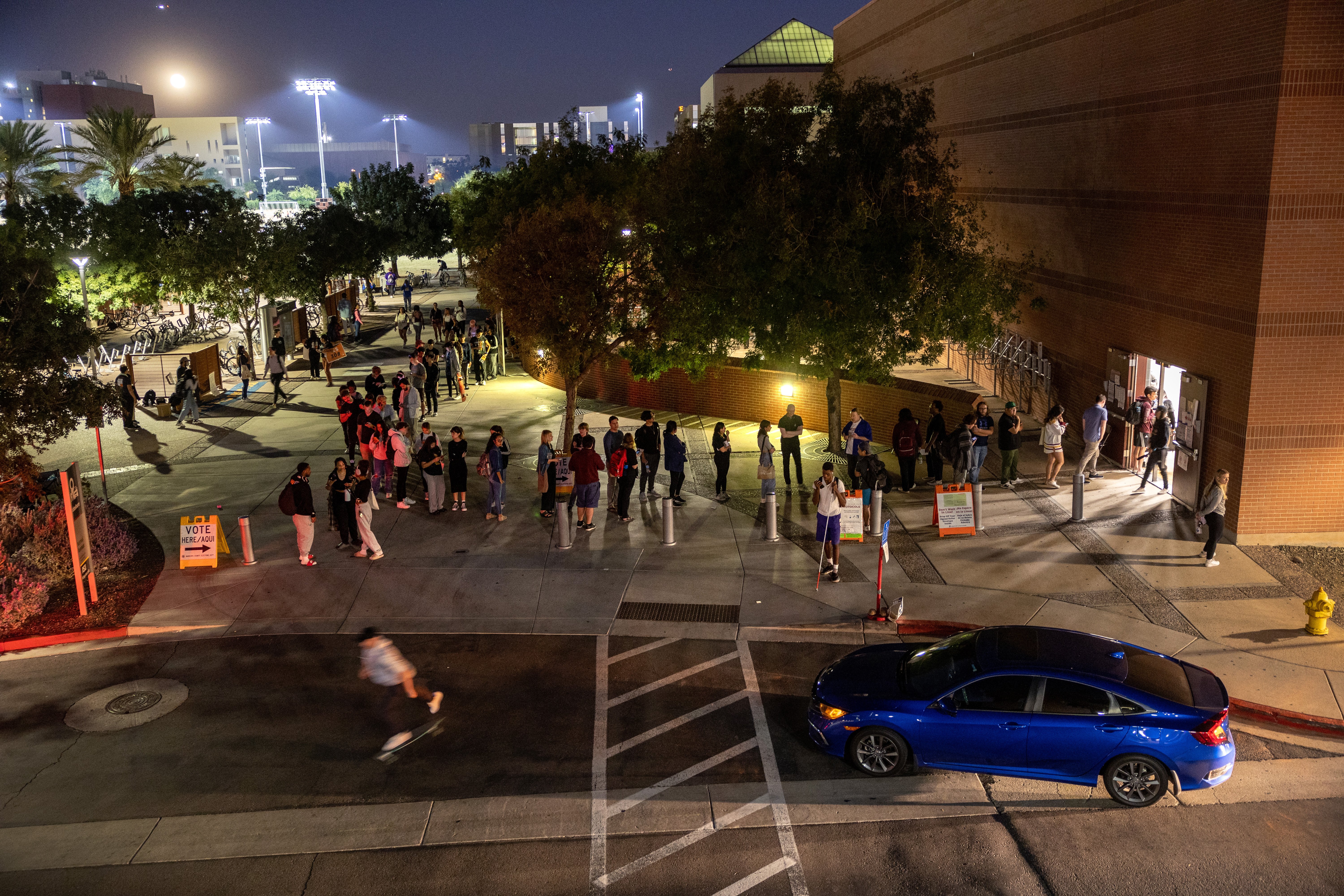 Lines of student voters weave across pavement outside a polling location at night