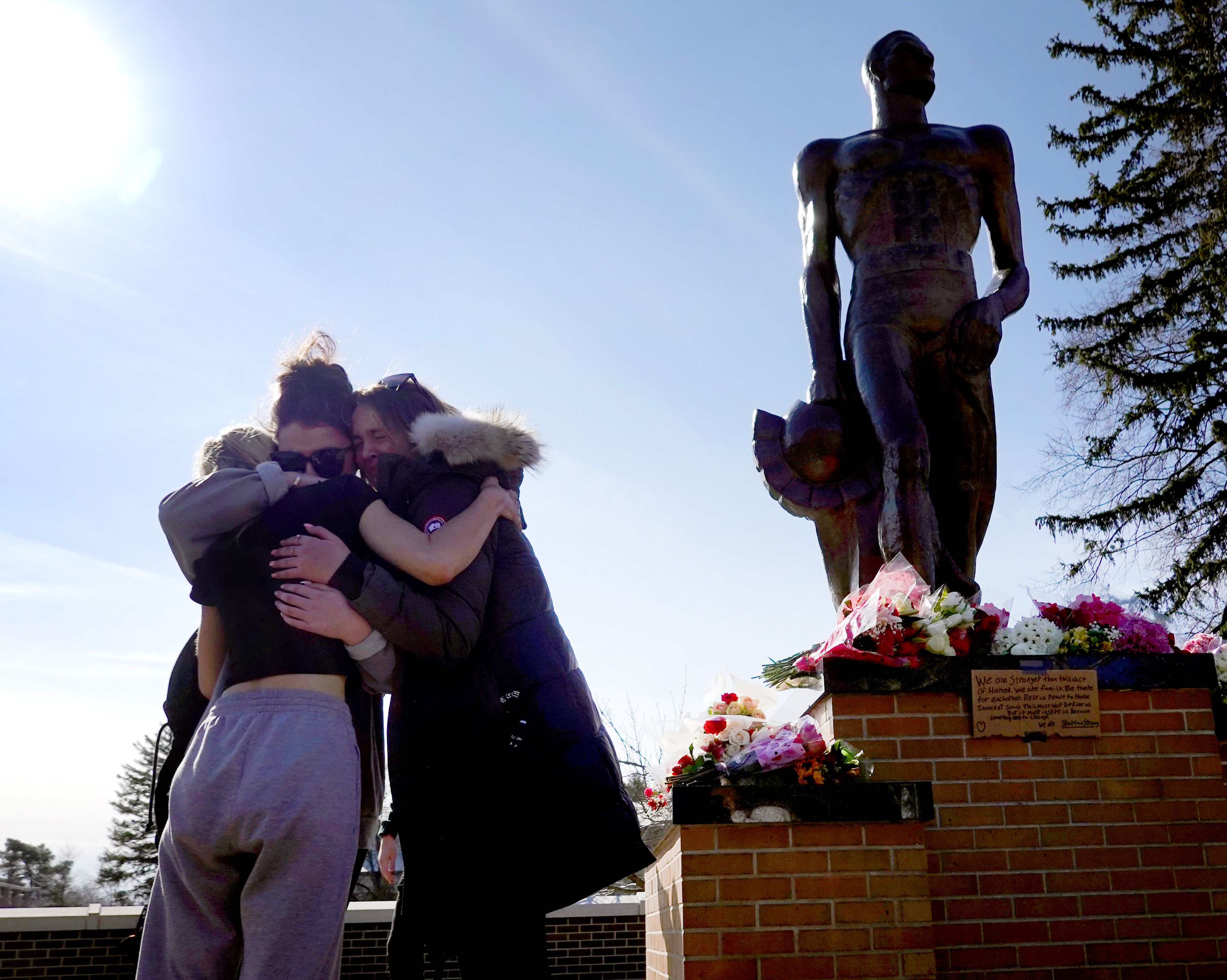 Students gather near a statue that has become an impromptu memorial on the Michigan State campus