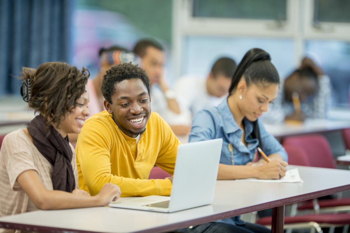 Three darker-skinned students in a seminar room.