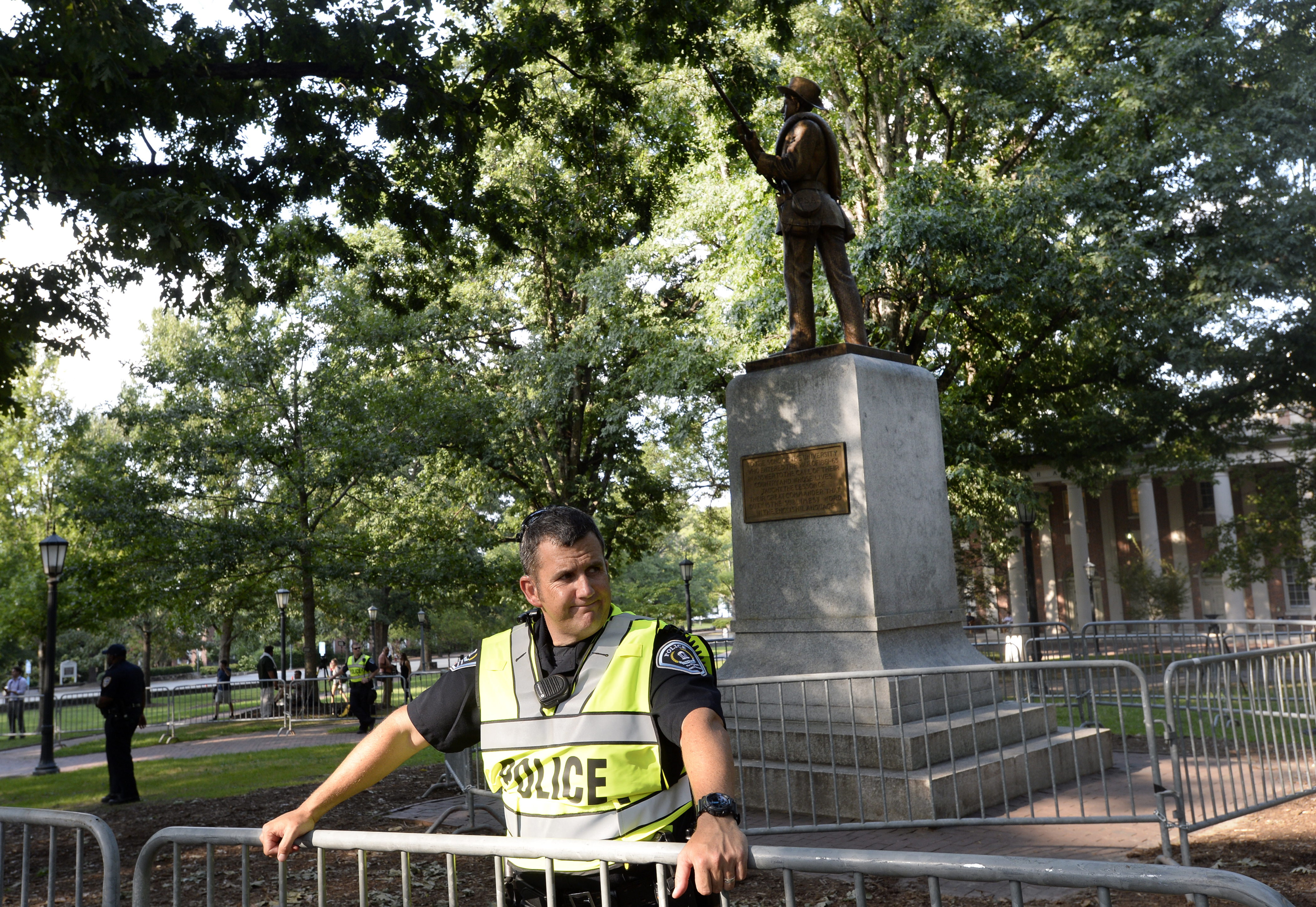 A police officer stands behind a gate in front of a statue