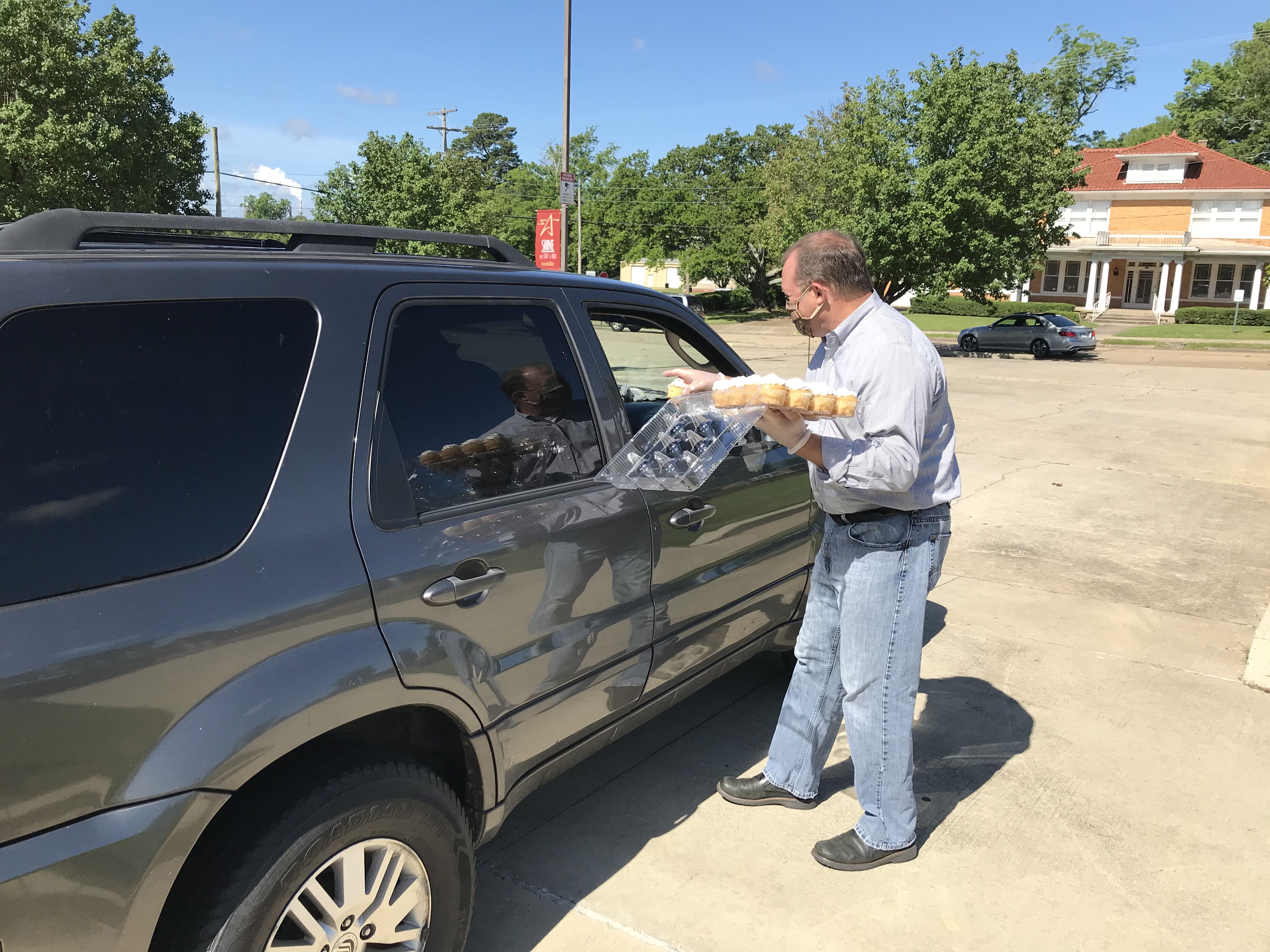 Wallace hands a cupcake through a car window during his drive-through birthday celebration last May. Photo courtesy of Bentley Wallace