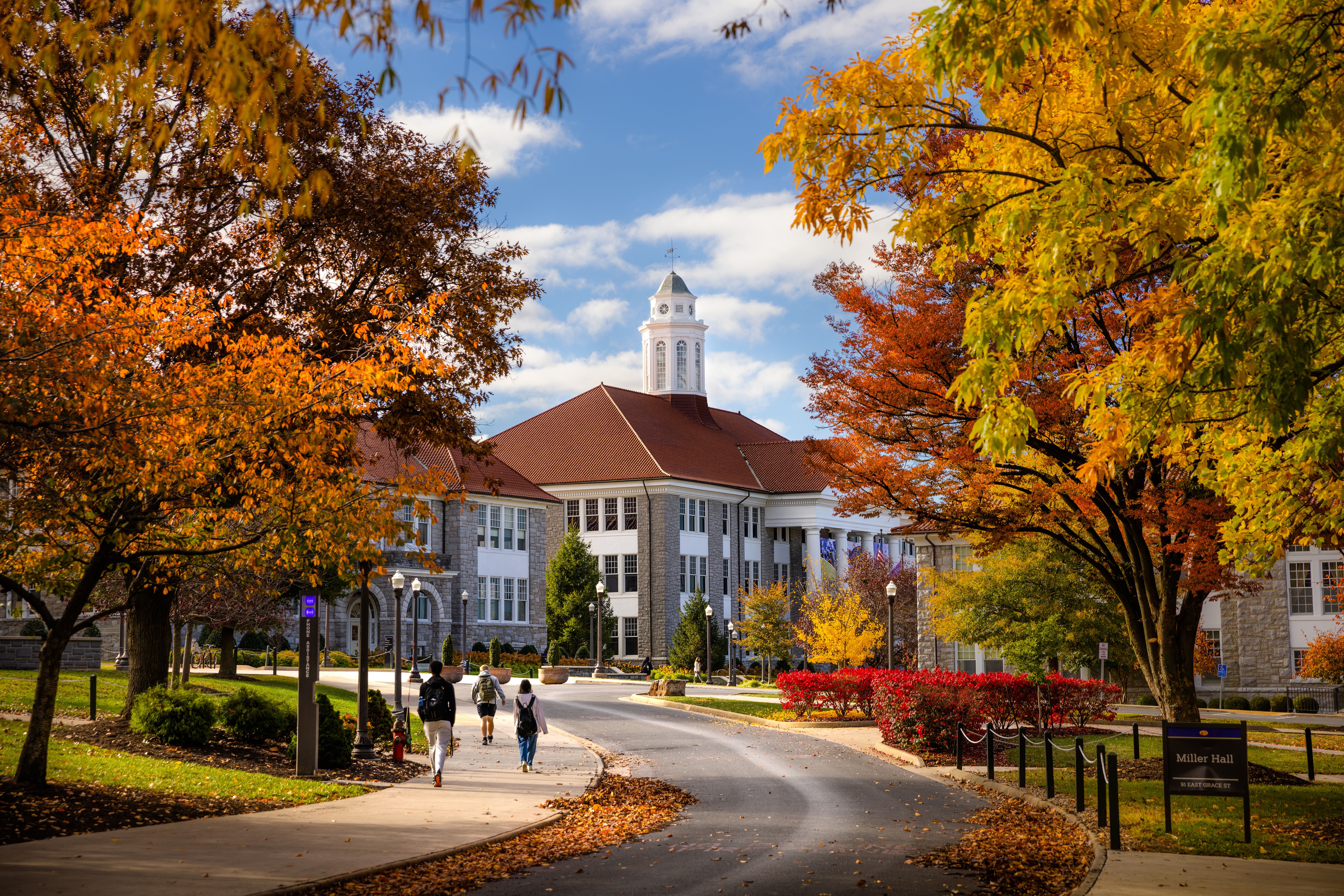 Students walking along a street at James Madison University in autumn.