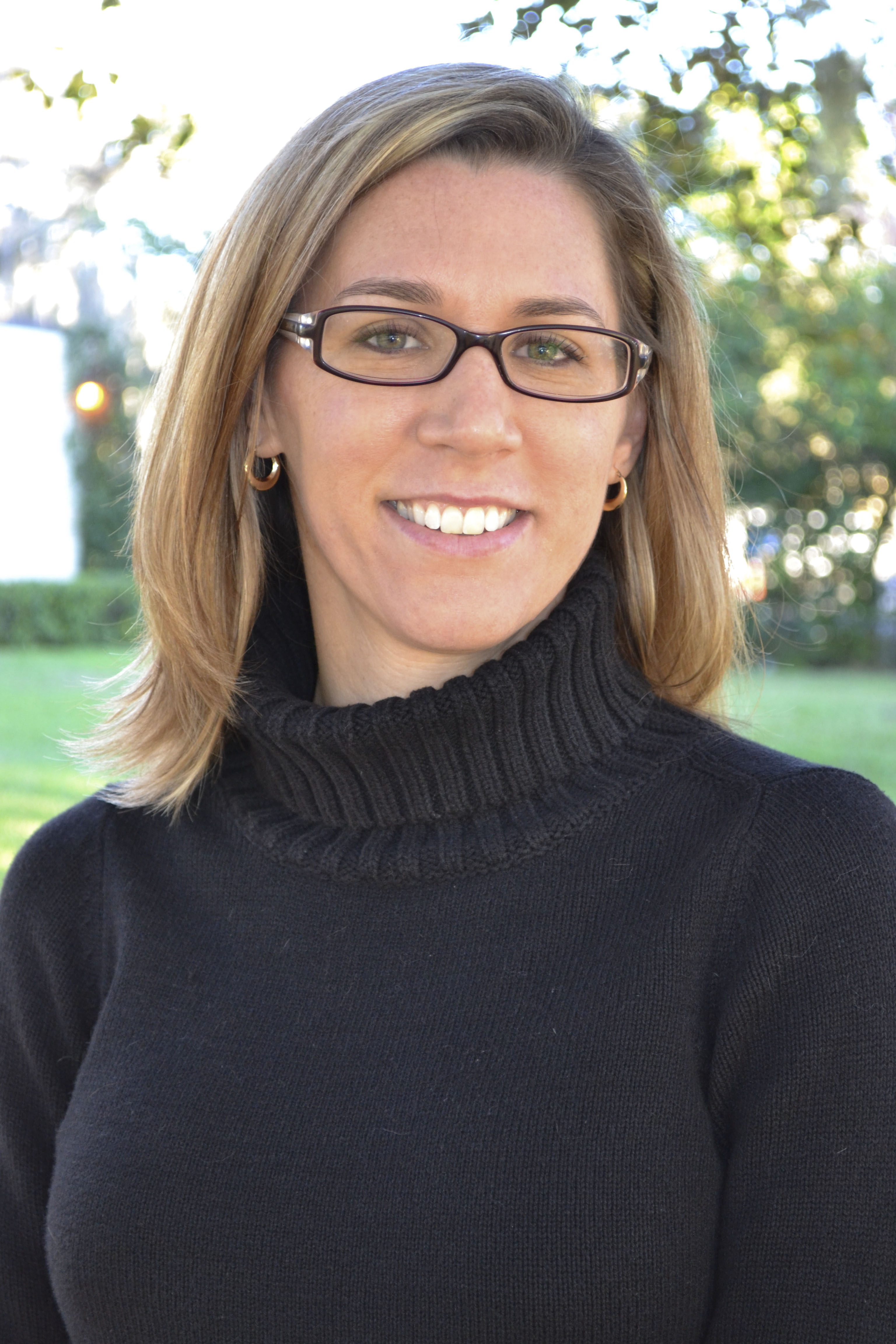 Meggen Sixbey, a white woman with light brown hair and glasses wearing a black turtleneck.