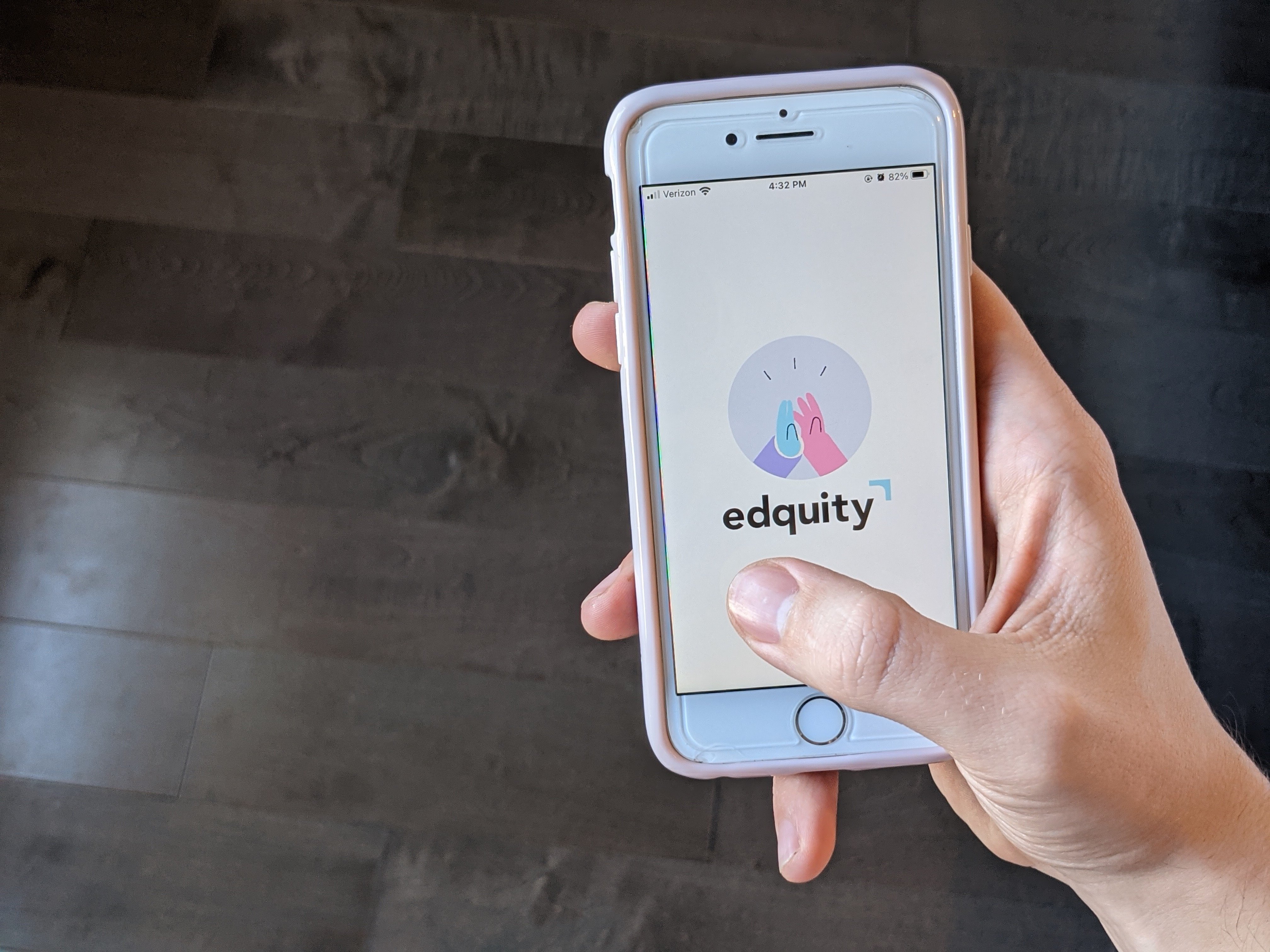 A person holds a phone with the Edquity app open. 