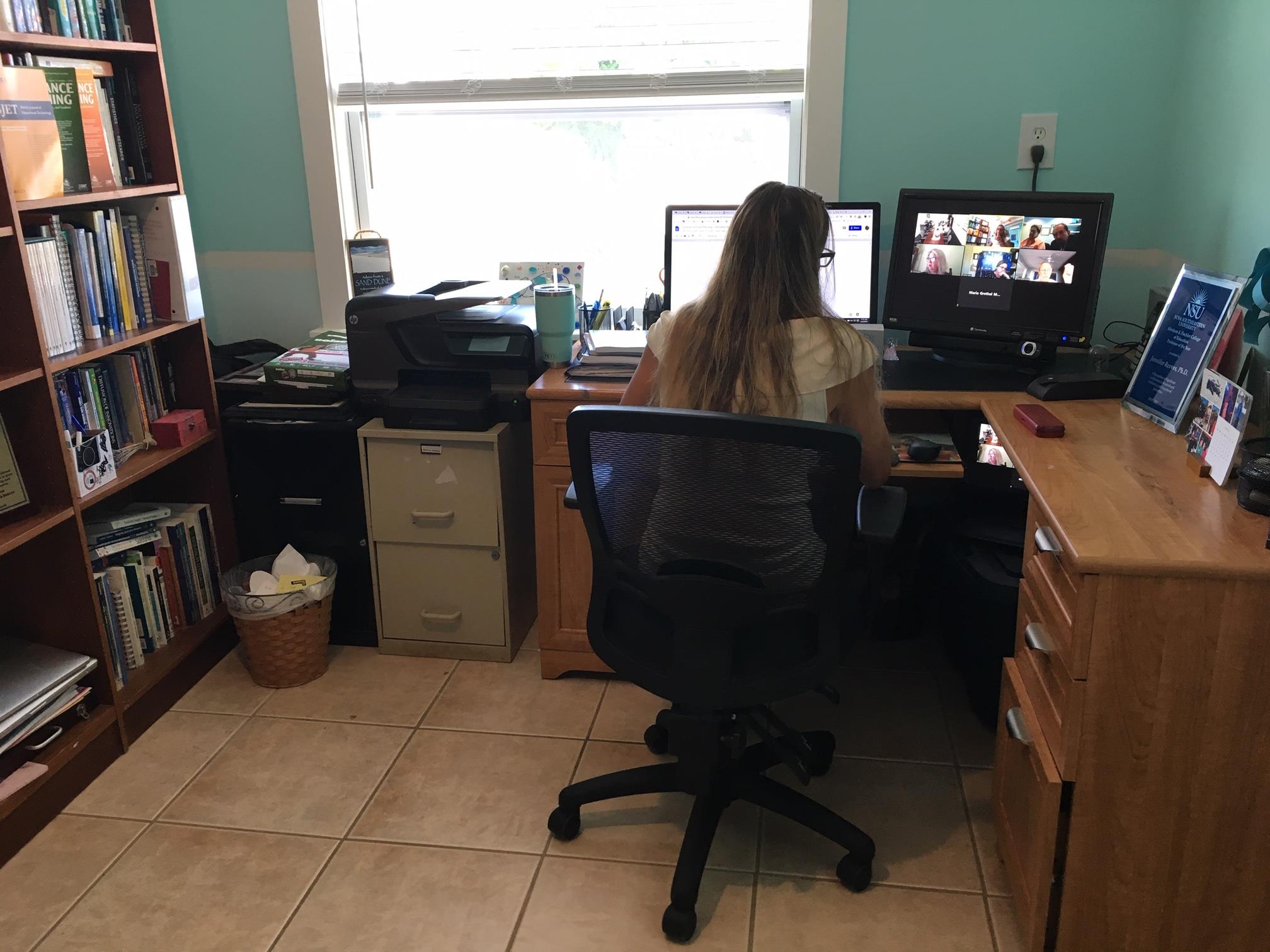 Jennifer Reeves' workspace includes two monitors and a nearby bookshelf