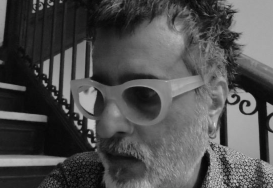 Aneil Rallin, a person of color with gray hair who is wearing thick plastic-framed glasses.