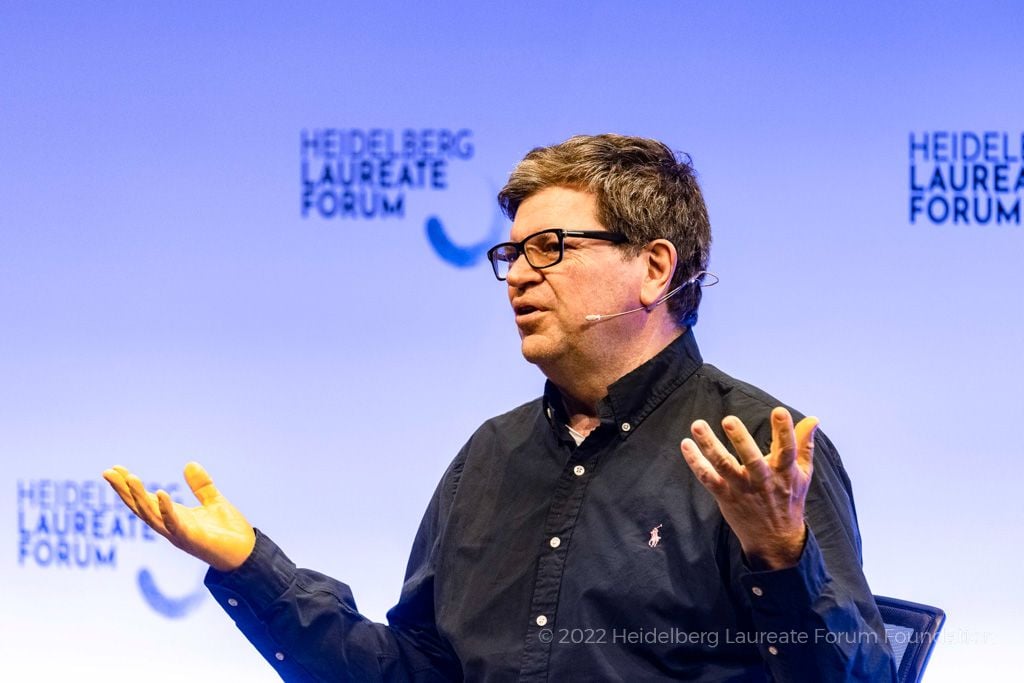 Yann LeCun, a white man with dark hair and glasses who has a microphone reaching from his ear to his mouth.