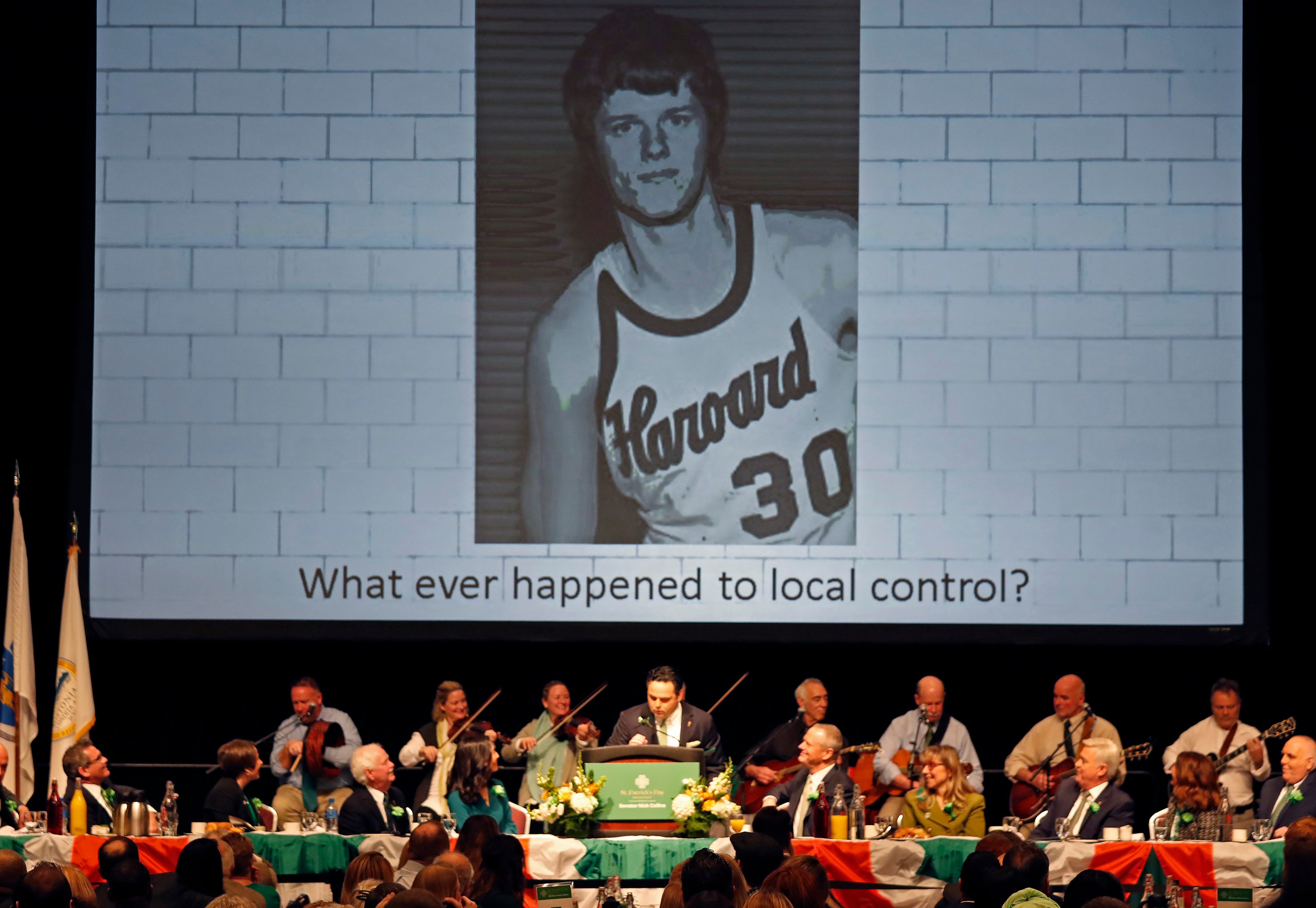 Charlie Baker is teased at a Boston political gathering with a photo of him in a Harvard basketball uniform.