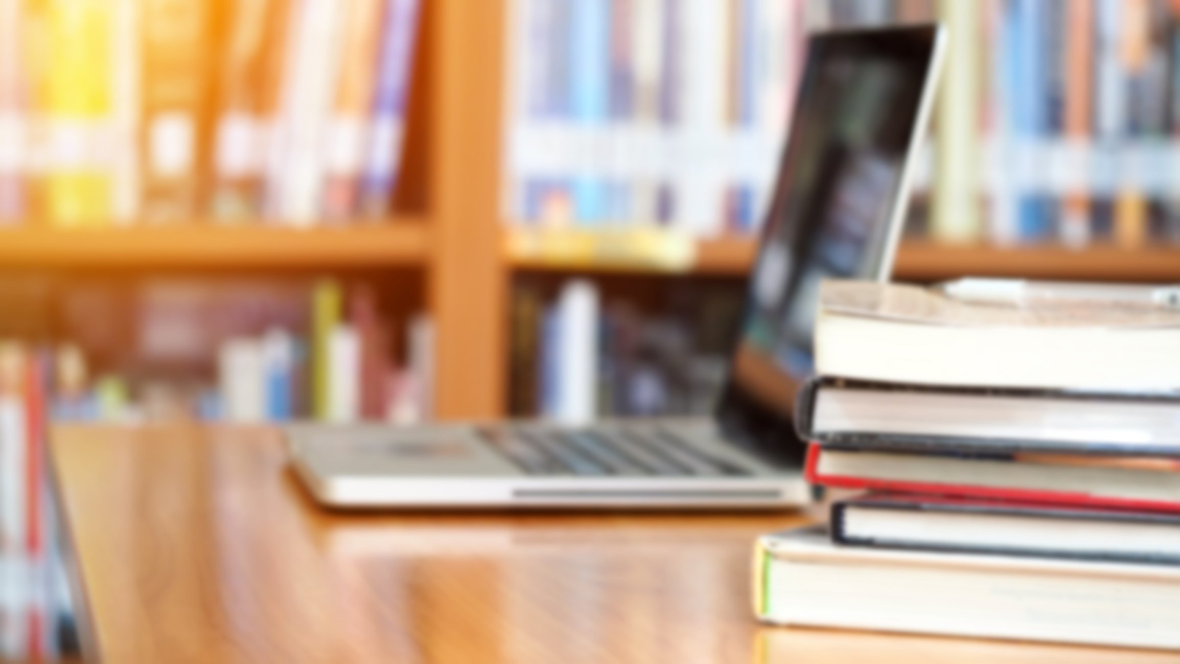 Image of a laptop and several textbooks.