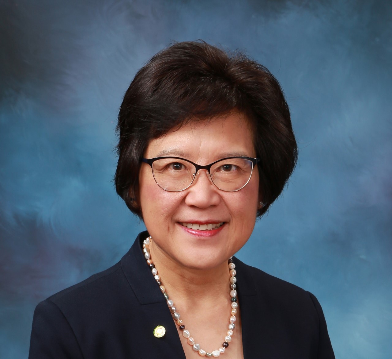 Pamela Lau, an Asian woman with dark hair who is wearing glasses and a pearl necklace.