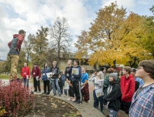 A male student tour guide addresses a group of prospective students.