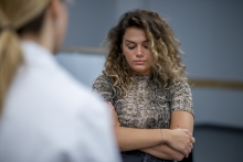 A young woman looks down as she talks to her therapist.